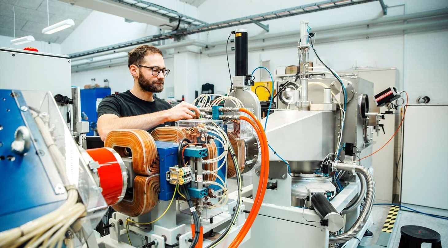 Mand arbejder med ion-maskine med store magneter