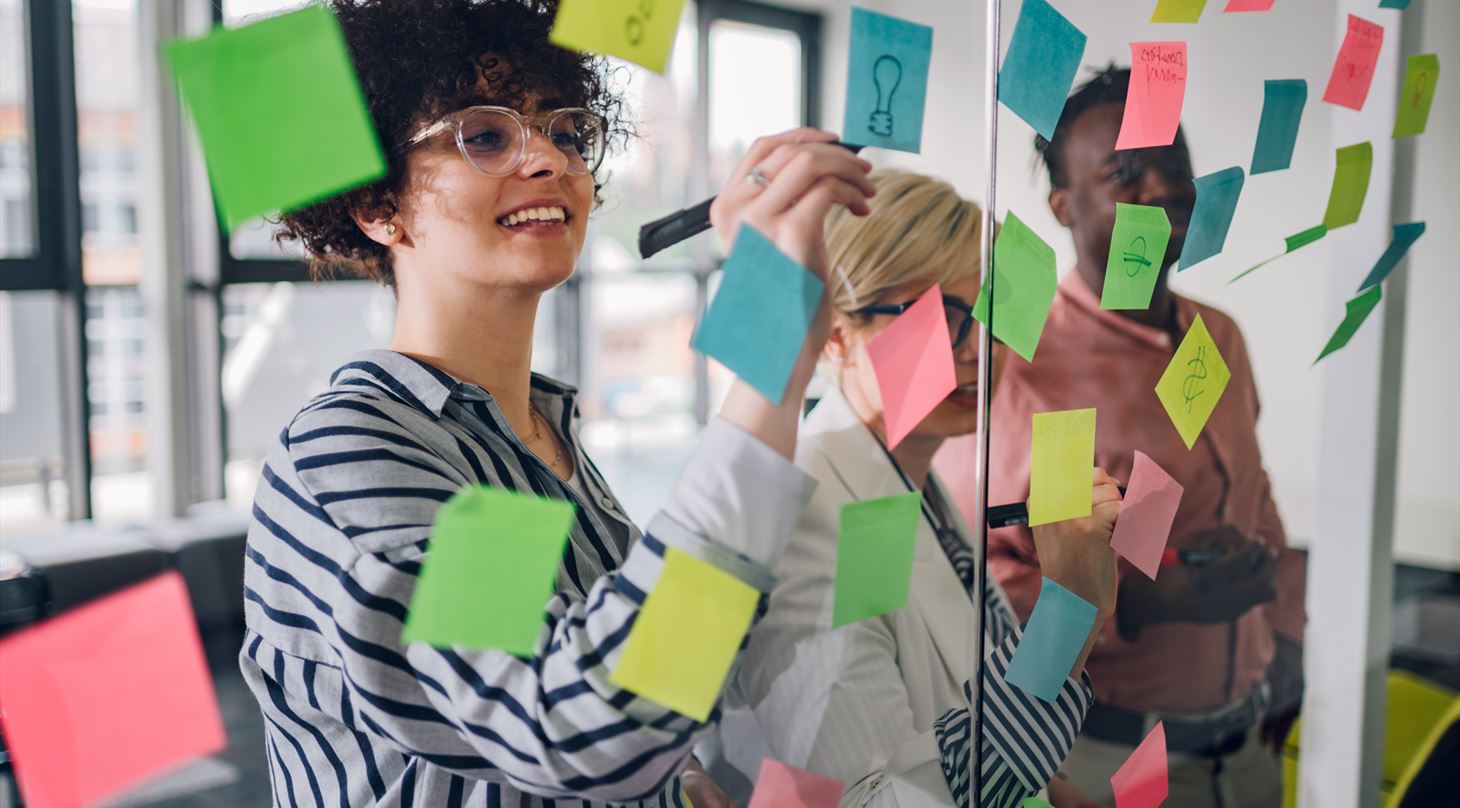 Billede af tre personer, der sætter post-its op på en glasvæg