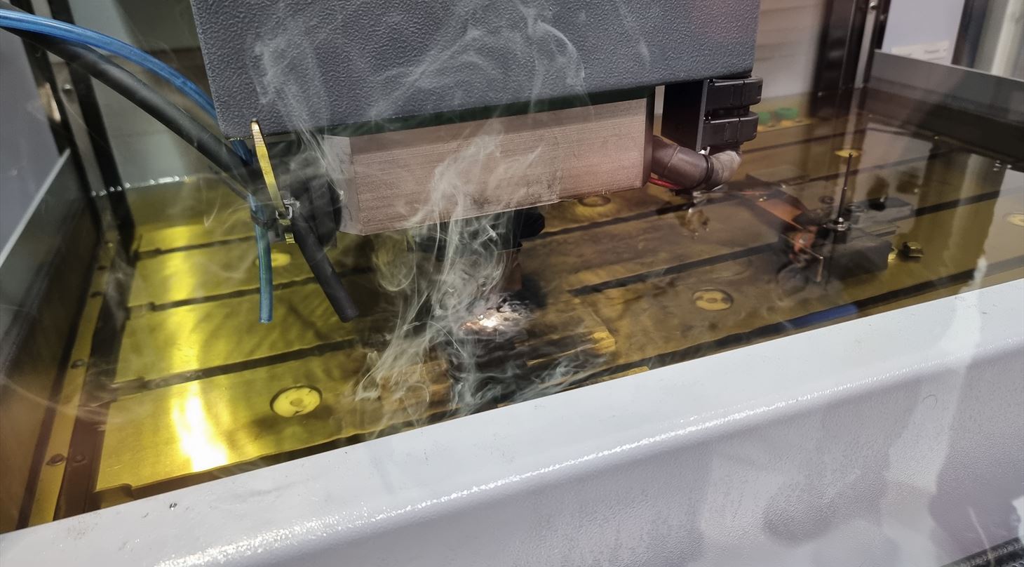 En CNC-maskine bearbejder metal med gnister og rg under processen.